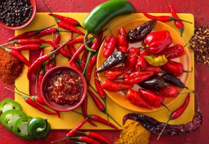 Assorted hot peppers including jalapeños, serranos, and cayenne growing in a sunny Cincinnati garden." 